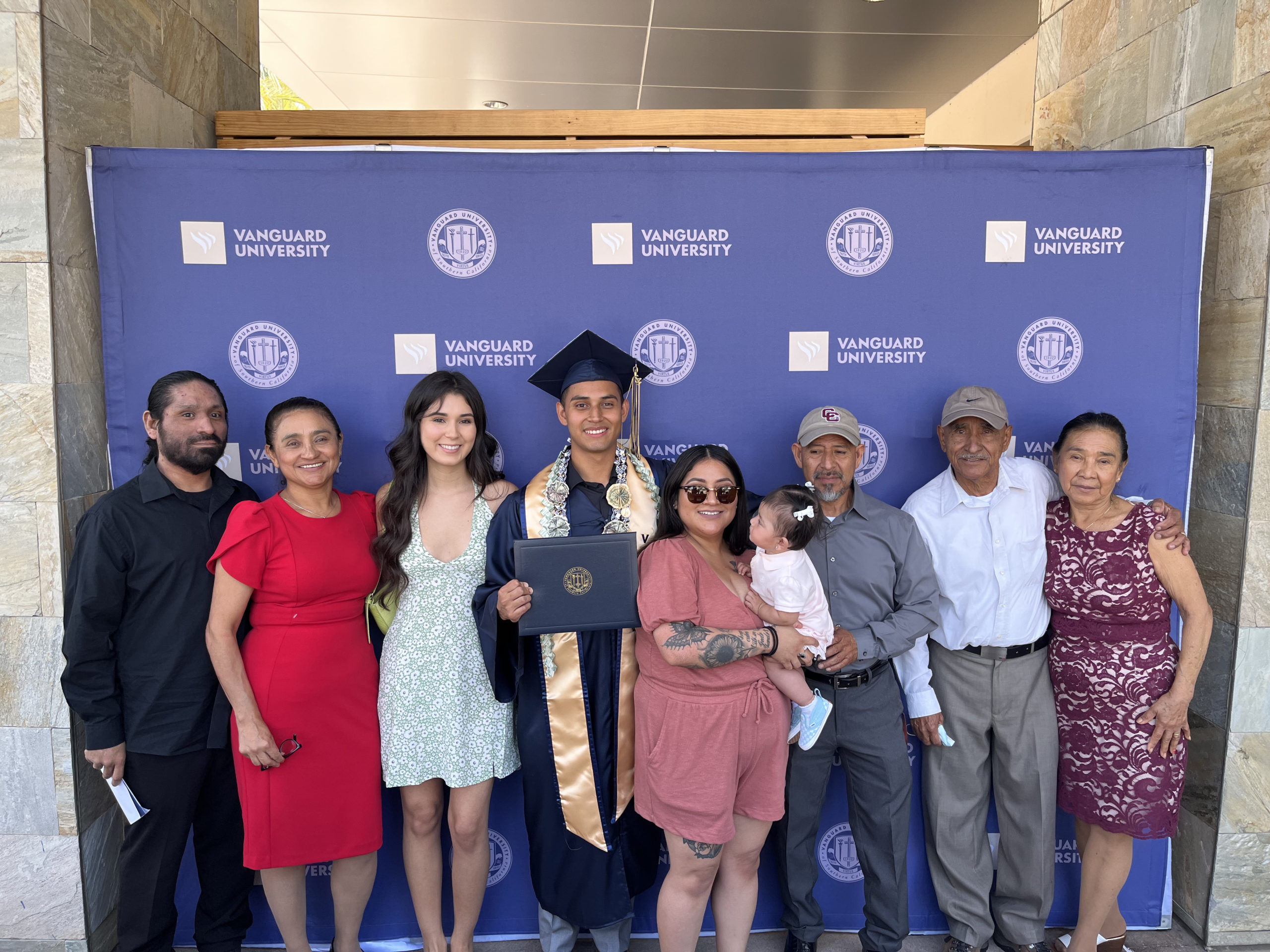 A Vanguard University student poses with his family at graduation 
