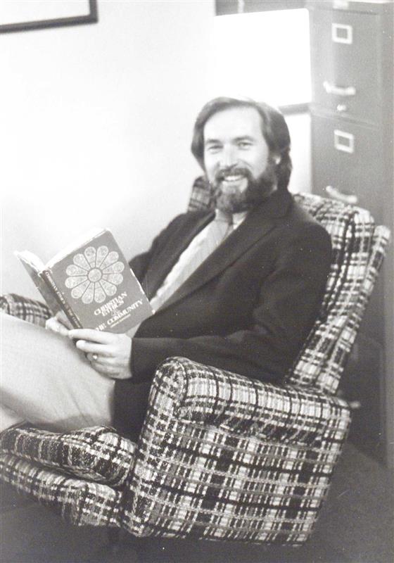 Dr. Murray Dempster reading a book and sitting in a chair in the 1980s.